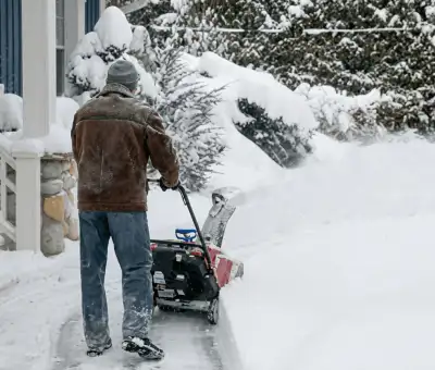 Residential snow removal technician using a snow blower to clear a home driveway and walkway in Green Bay, WI